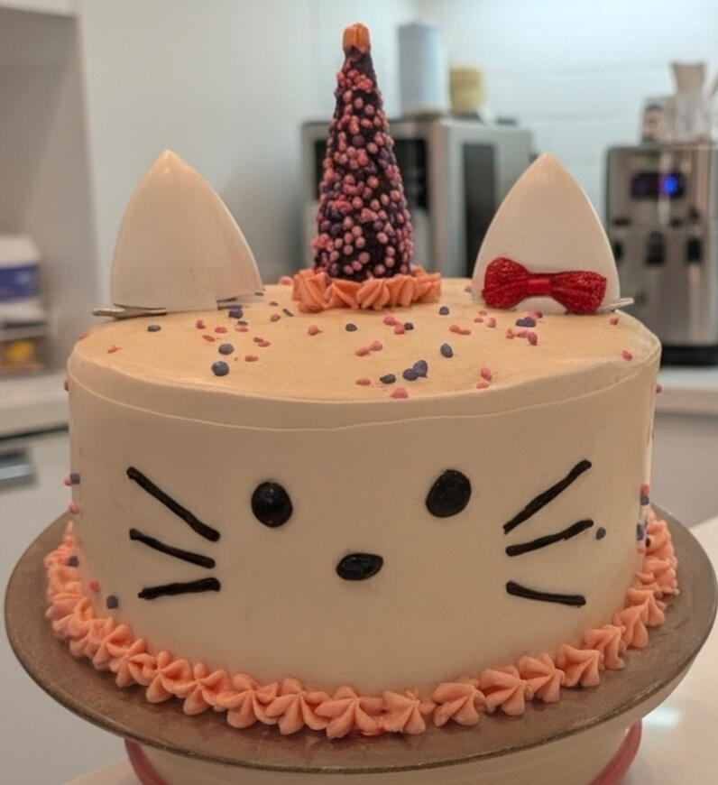 Custom kitty cat birthday cake with ears, whiskers, and a red bow by Rylee's Sunrise Bakery
