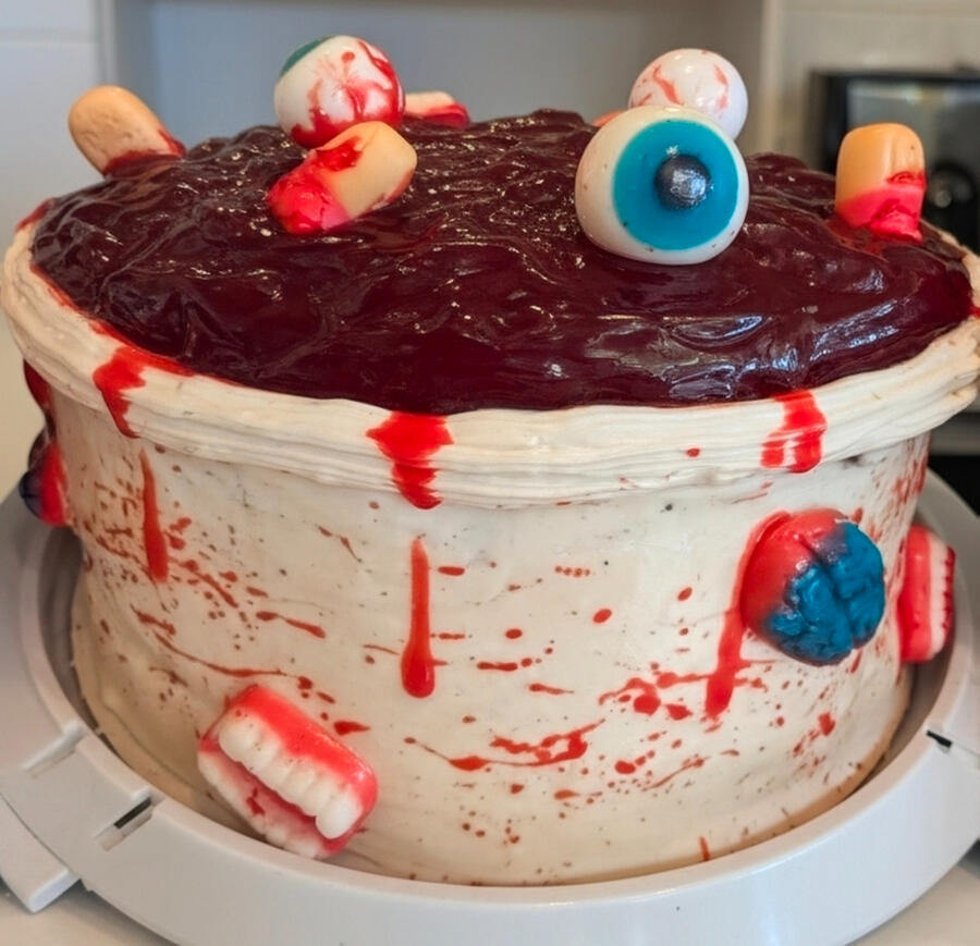 Spooky Halloween cake with red drip, candy eyeballs, and gummy teeth