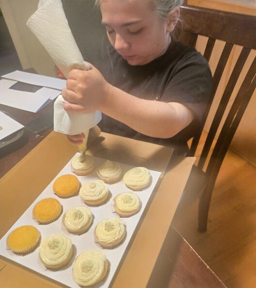 Rylee piping vanilla frosting onto a tray of homemade cookies