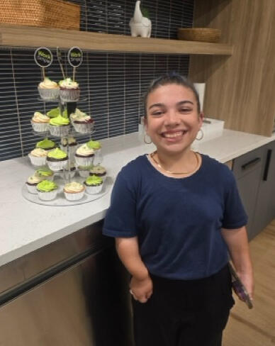 Rylee of Rylee's Sunrise Bakery with a tower of homemade cupcakes